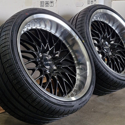 Set of black alloy wheels on a concrete floor