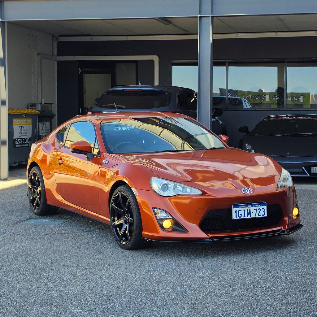 A metallic copper orange sports car parked inside a garage bay, with a large vertical banner reading 'd Speed ' hanging beside the open DSpeed DS-07 ds07 18x8.5 +35 5x100 alloy wheels rims concave gloss black
