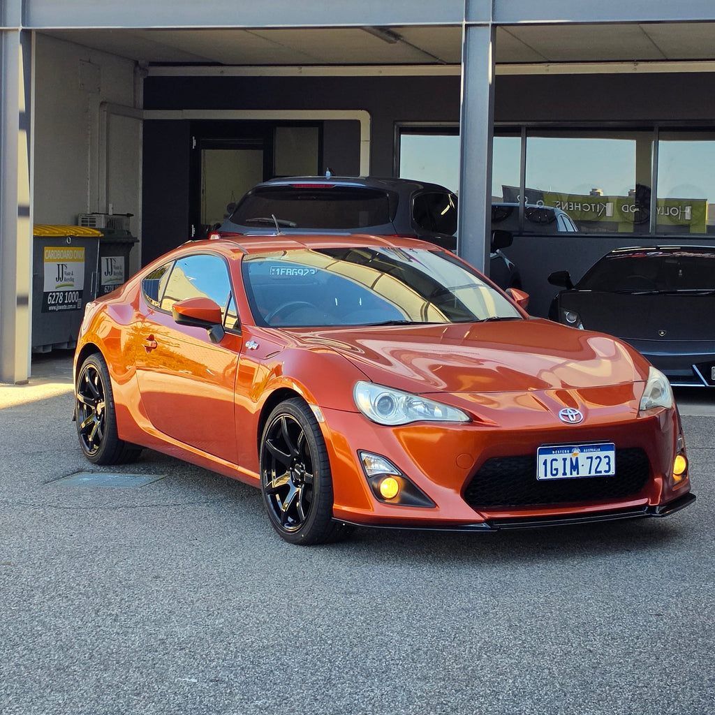 A metallic copper orange sports car parked inside a garage bay, with a large vertical banner reading 'd Speed ' hanging beside the open DSpeed DS-07 ds07 18x8.5 +35 5x100 alloy wheels rims concave gloss black