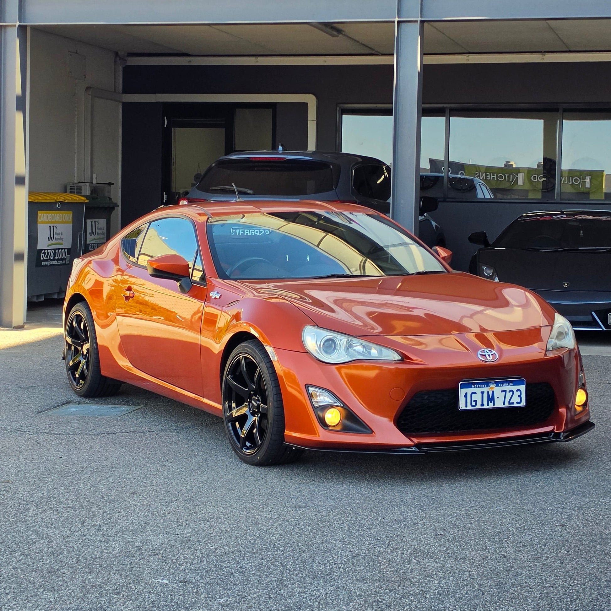 A metallic copper orange sports car parked inside a garage bay, with a large vertical banner reading 'd Speed ' hanging beside the open DSpeed DS-07 ds07 18x8.5 +35 5x100 alloy wheels rims concave gloss black