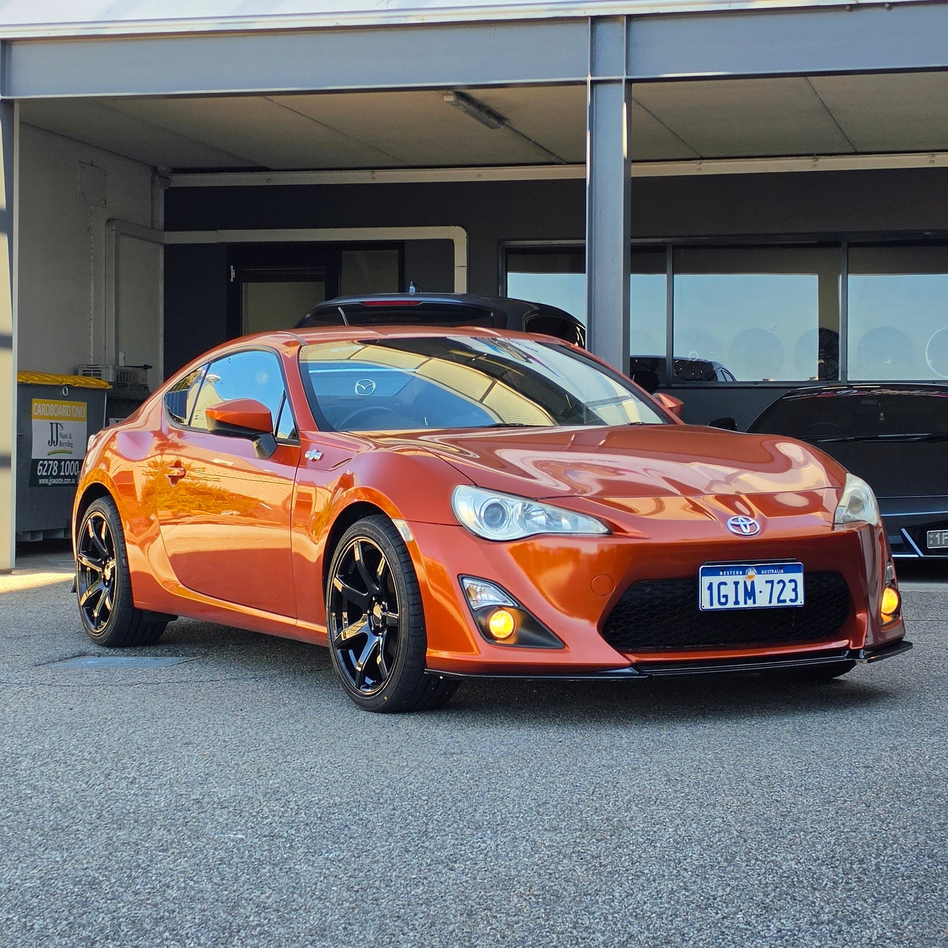 A metallic copper orange sports car parked inside a garage bay, with a large vertical banner reading 'd Speed ' hanging beside the open DSpeed DS-07 ds07 18x8.5 +35 5x100 alloy wheels rims concave gloss black