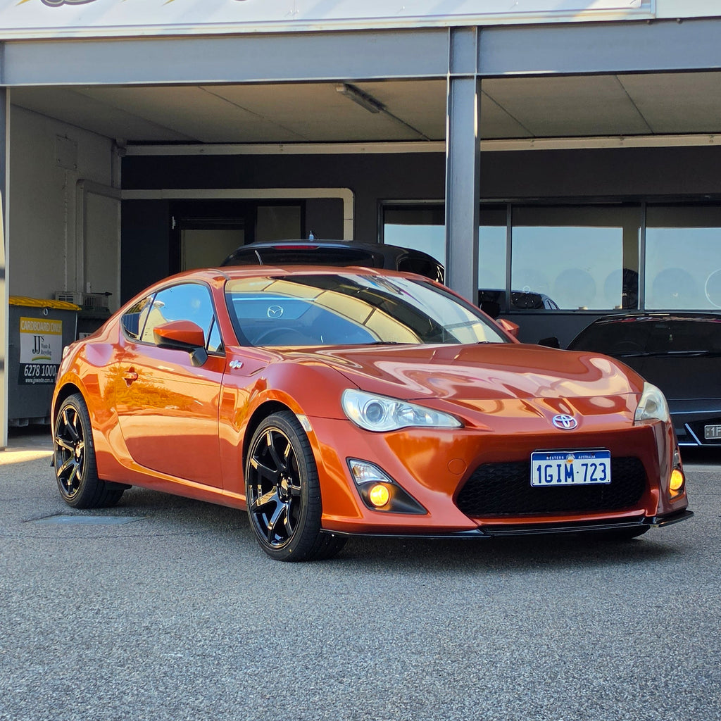 A metallic copper orange sports car parked inside a garage bay, with a large vertical banner reading 'd Speed ' hanging beside the open DSpeed DS-07 ds07 18x8.5 +35 5x100 alloy wheels rims concave gloss black