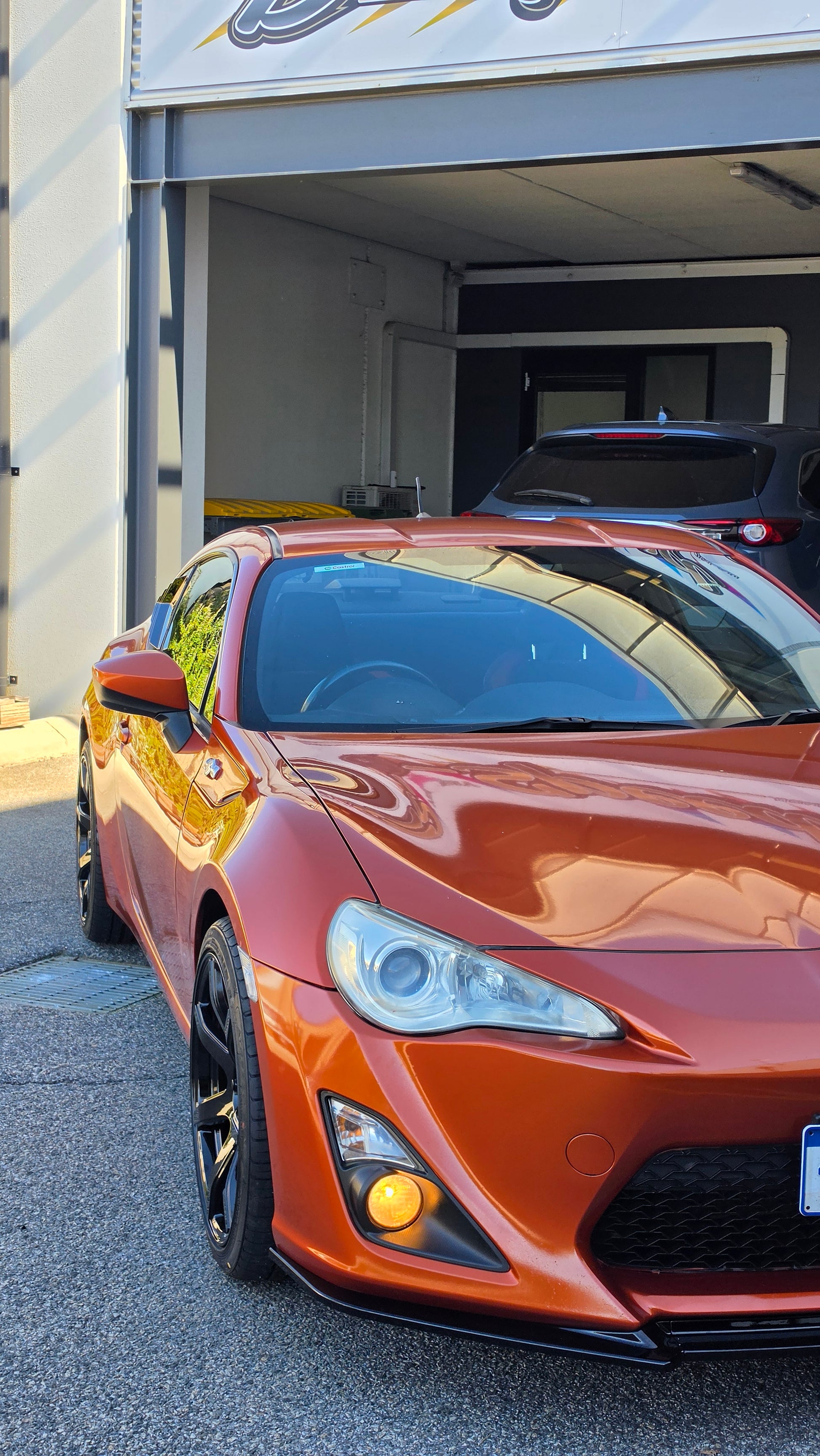 A metallic copper orange sports car parked inside a garage bay, with a large vertical banner reading 'd Speed ' hanging beside the open DSpeed DS-07 ds07 18x8.5 +35 5x100 alloy wheels rims concave gloss black