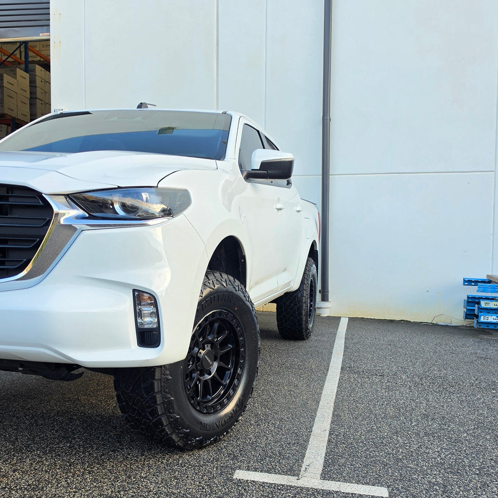 A white Mazda bt50 bt-50 pickup truck parked on asphalt in front of a dspeed d-speed industrial building with a garage door. xt-1 wheel 4x4 rims 285 tyres 285/70r17 at xt rt mt all terrain