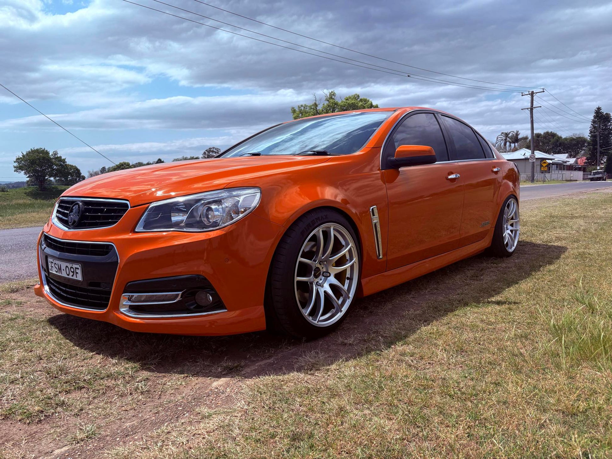 Orange Holden Commodore VF on DSpeed DS02 wheels 19x9.5 car parked on a grassy area with a cloudy sky.