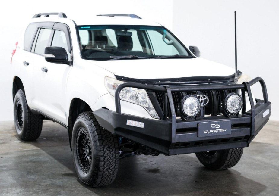 A white Toyota Land Cruiser PRADO SUV with a black front bumper guard, auxiliary lights, and off-road tires, photographed in a studio setting. 4X4 WHEELS DSPEED OFFROAD Off road MH-2 mh2 17x8.5 17inch 4x4 wheels rims deep dish black satin black