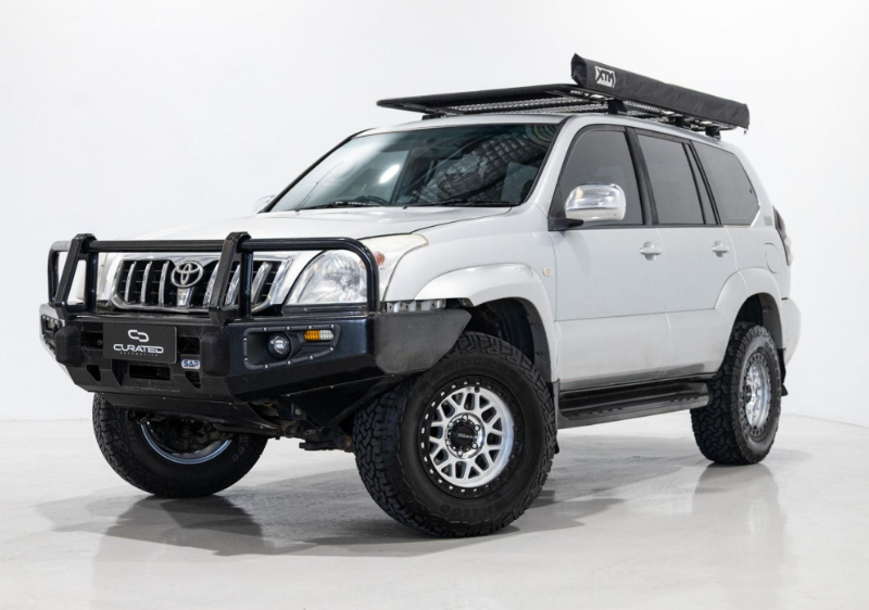 A white Toyota Land Cruiser PRADO SUV with a black front bull bar, black roof rack, and D-Speed MH-1 dspeed mh1 machined silver with black ring wheels rims alloys 17x8.5 17x9 with 275/70R17 Roadcruza RA1100 all terrain tyres off road offroad 4x4