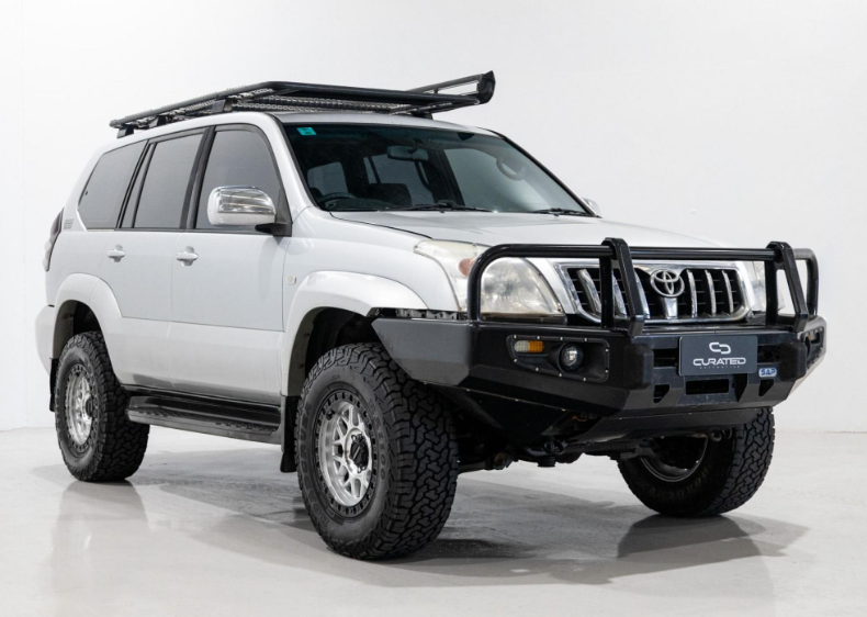 A white Toyota Land Cruiser PRADO SUV with a black front bull bar, black roof rack, and D-Speed MH-1 dspeed mh1 machined silver with black ring wheels rims alloys 17x8.5 17x9 with 275/70R17 Roadcruza RA1100 all terrain tyres off road offroad 4x4