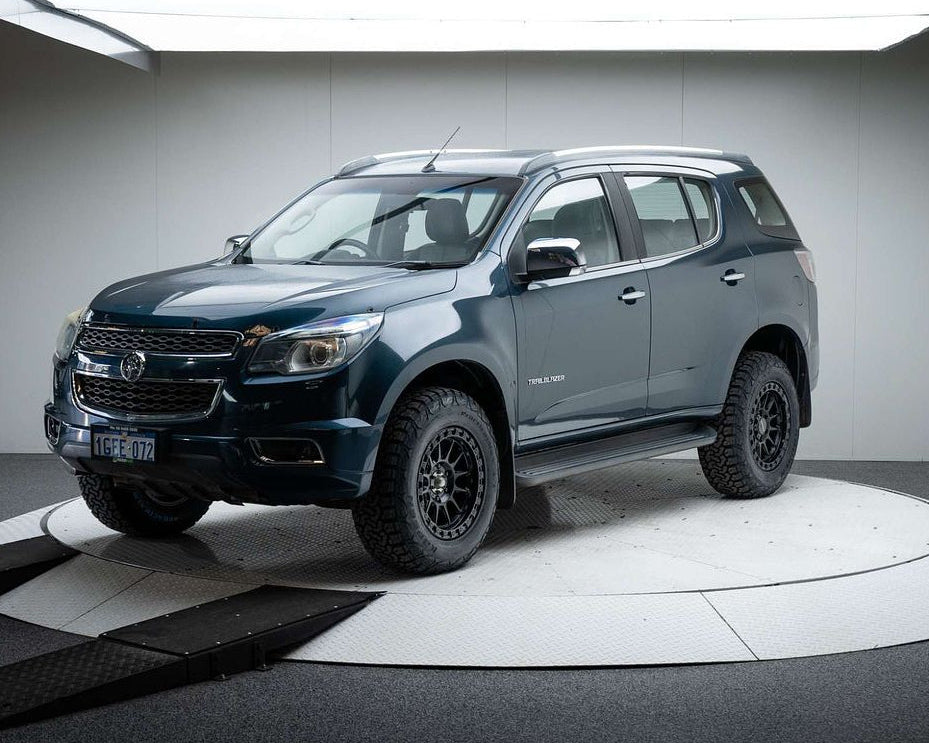 A dark metallic blue-gray Chevrolet Colorado pickup truck with off-road tires and black wheels, displayed on a circular white platform inside a studio setting. dspeed xt1 D-Speed XT-1 wheel with AT all terrain tyres 4x4 wheels rims off road offroad
