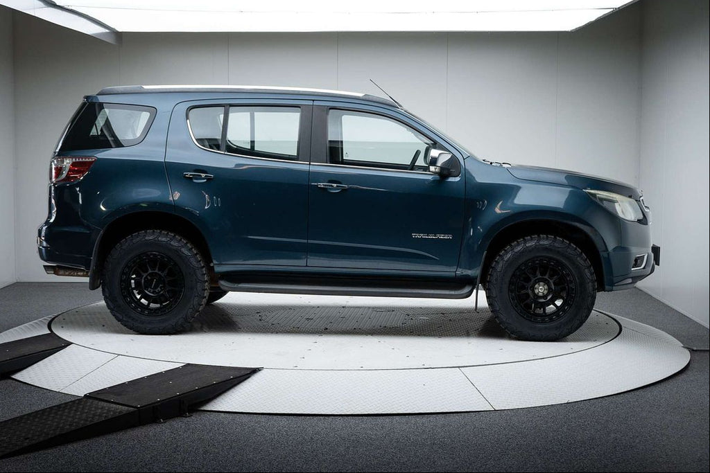 A dark metallic blue-gray Chevrolet Colorado pickup truck with off-road tires and black wheels, displayed on a circular white platform inside a studio setting. dspeed xt1 D-Speed XT-1 wheel with AT all terrain tyres 4x4 wheels rims off road offroad