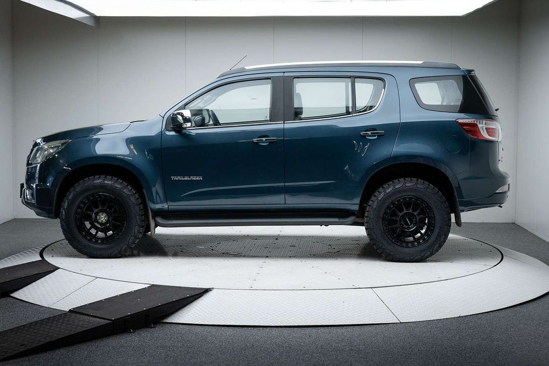 A dark metallic blue-gray Chevrolet Colorado pickup truck with off-road tires and black wheels, displayed on a circular white platform inside a studio setting. dspeed xt1 D-Speed XT-1 wheel with AT all terrain tyres 4x4 wheels rims off road offroad
