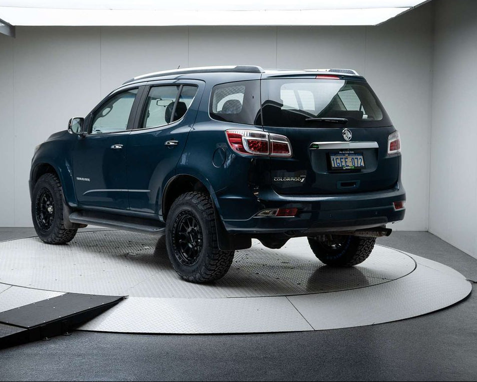 A dark metallic blue-gray Chevrolet Colorado pickup truck with off-road tires and black wheels, displayed on a circular white platform inside a studio setting. dspeed xt1 D-Speed XT-1 wheel with AT all terrain tyres 4x4 wheels rims off road offroad