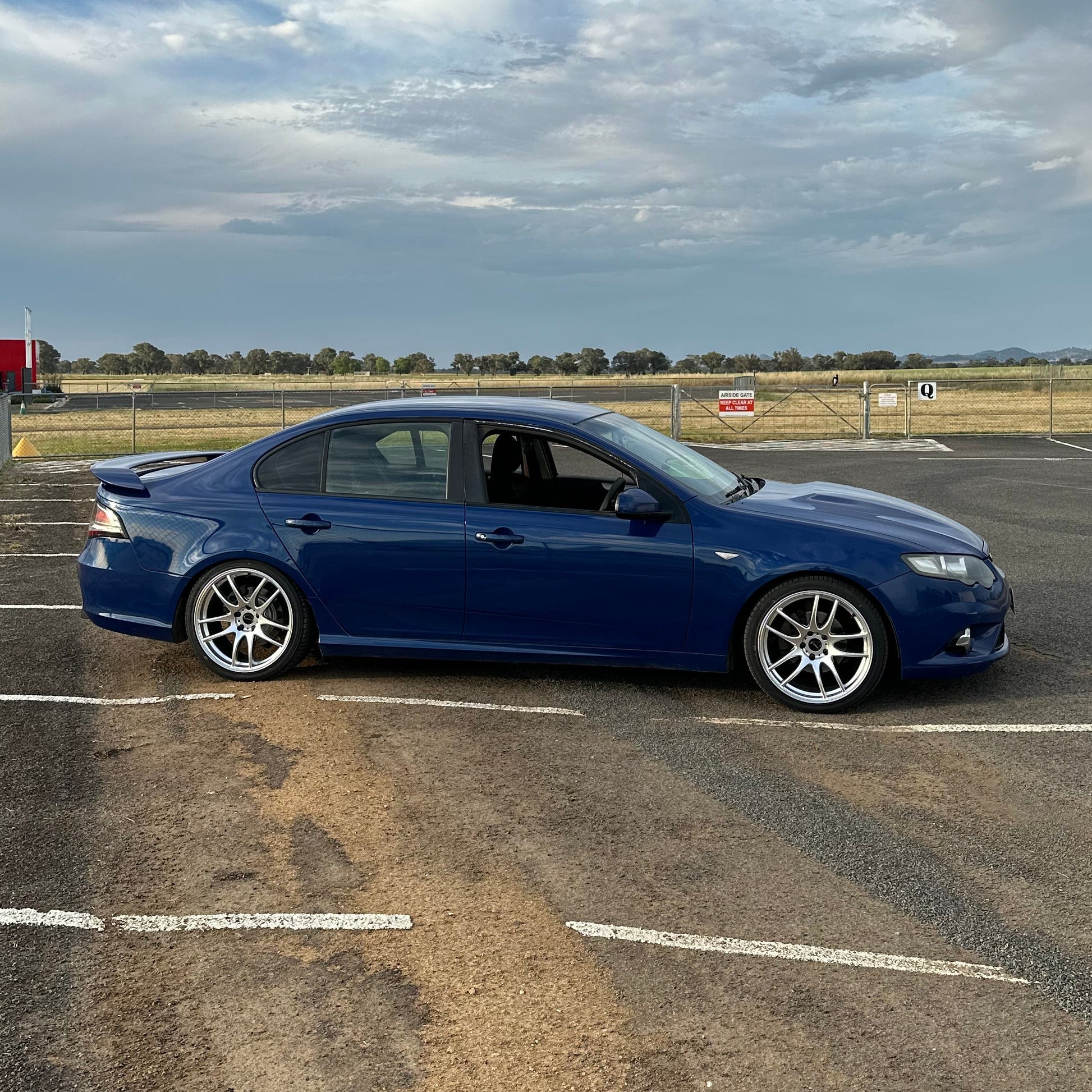 Blue car parked on a city street at night with buildings and lights in the background. Ford FG Falcon dspeed D-Speed DS02 DS-02 wheels 19x8.5 tyre package