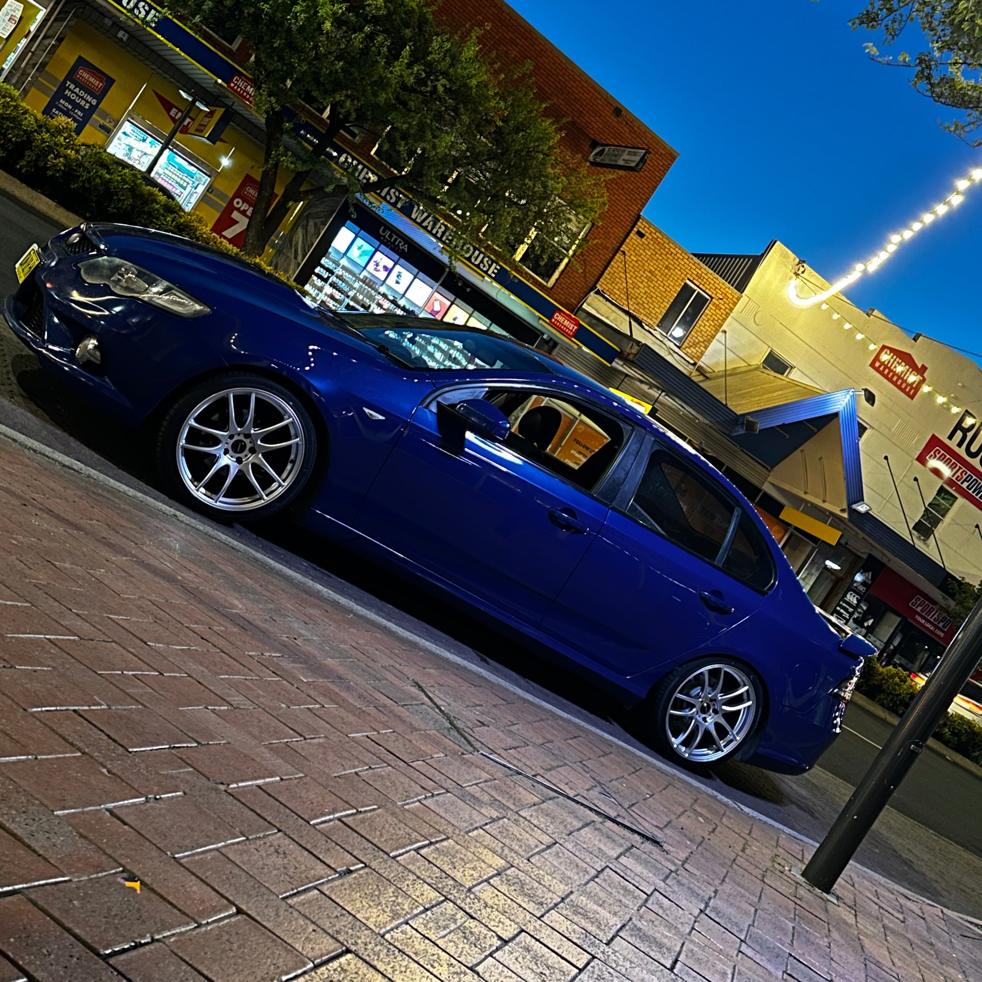 Blue car parked on a city street at night with buildings and lights in the background. Ford FG Falcon dspeed D-Speed DS02 DS-02 wheels 19x8.5 tyre package